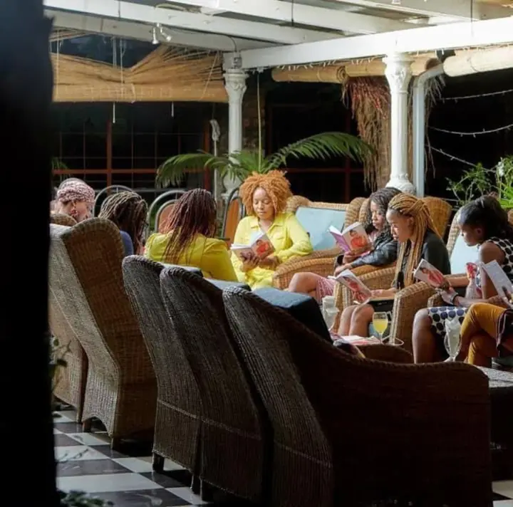 Women sit together reading books in a lounge setting.
