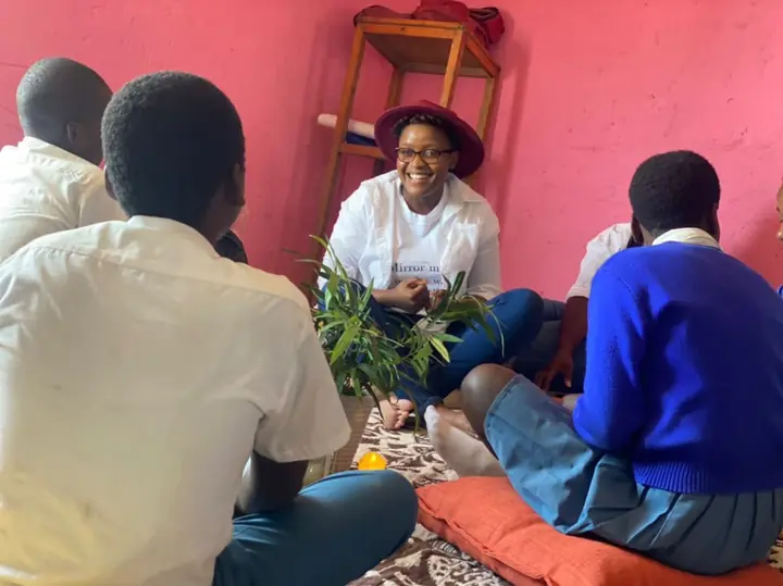 A facilitator smiles while sitting in a circle with students.