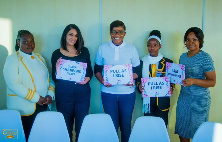 Women and students pose with affirmation signs.