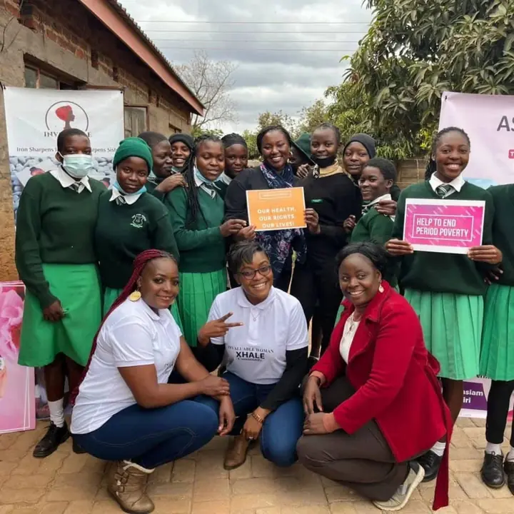 Students and facilitators hold signs about health rights and ending period poverty