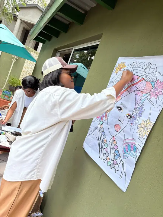 A woman colouring a large portrait during a reflective activity