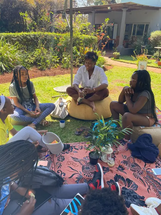 Women seated outdoors on beanbags in a small reflective circle