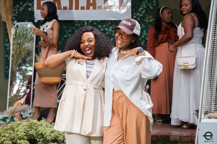 Two women smiling together at the entrance to an event.